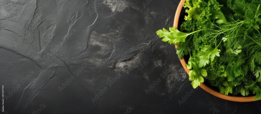 Poster top view of salad leaves mixed in a black bowl on a dark slate, stone, or concrete surface, with amp