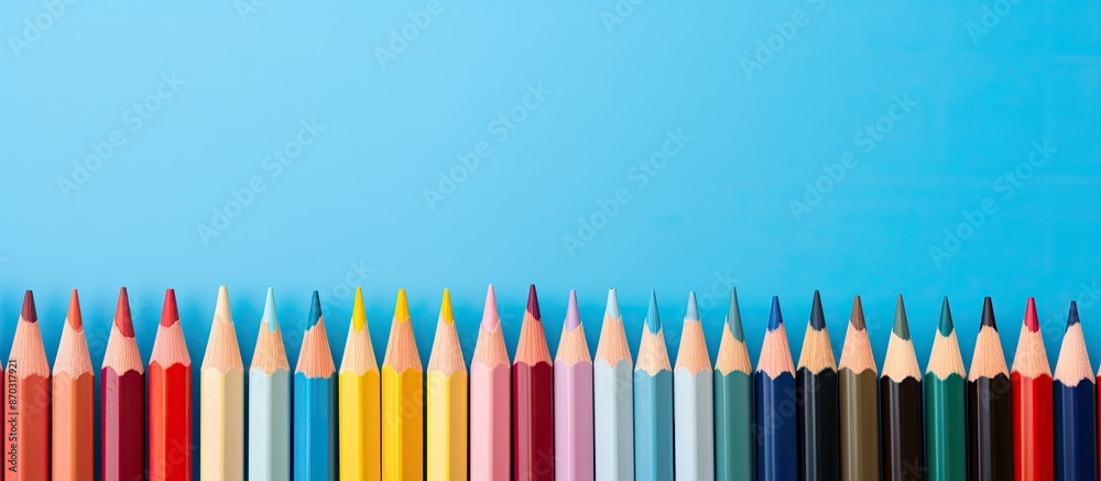 Poster colorful pencils lined up against a blue backdrop with copy space image.