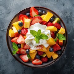 Tasty fruit salad with whipped cream and mint leaves.