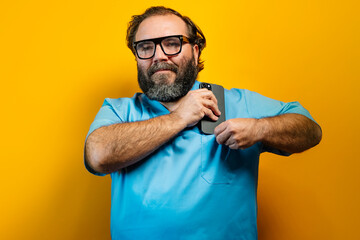 Doctor in blue coat on yellow background using a smartphone.
