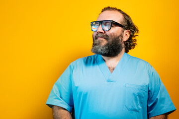 Friendly doctor smiling in blue coat on yellow background.
