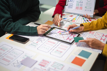 Close up view of UI developer team brainstorming on their project with laptop, smartphone and digital tablet.