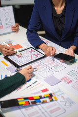 Close up view of UI developer team brainstorming on their project with laptop, smartphone and...