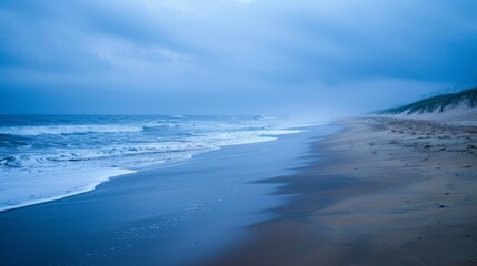 Fototapeta premium Watching the rain fall on a quiet beach, the ocean and sky blending into a misty horizon, brings a sense of peace and solitude.