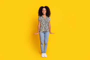 Fototapeta premium Portrait of glamour young miniature woman curly hair in zebra print shirt and jeans posing like small isolated on yellow color background