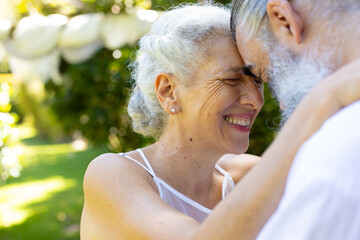 Embracing outdoors, smiling senior bride and groom at wedding