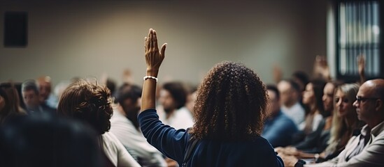 A young woman is raising her hand to ask a question at a business training session held in a conference room with a blank copy space image.