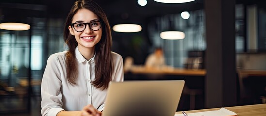 Fototapeta premium Portrait of a cheerful young businesswoman at her desk with a laptop, promoting online teaching for remote education with copy space image.