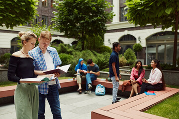 Group of diverse students, boys and girls of different nationality studying outdoors the university campus. Multiracial friends. Concept of education, university, multicultural students, unity