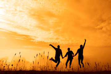 Silhouette of 3 three happy women jumping playing on green field at sunset time. people silhouettes...