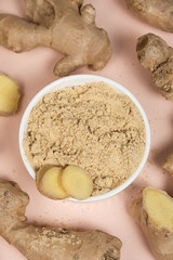 Ground ginger root powder natural spice seasoning on pink background