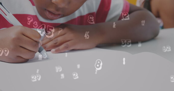 Image of numbers over african american schoolboy writing