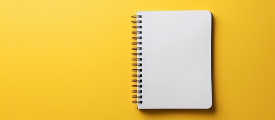 A white notebook against a yellow backdrop with space for writing or displaying images. image with copy space