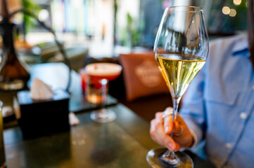 Close-up of a hand holding a glass of white wine, with an out-of-focus background.
