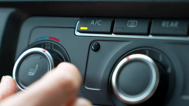 Woman hand pressing button to turn on air conditioner in car, close-up