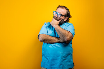 The doctor in a blue coat on a yellow background and thoughtful.