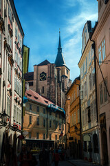 Obraz premium Prague, Czech Republic - building facades, towers, gothic spires and a clock on a street in Prague