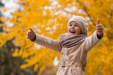 Happy caucasian girl in a beige coat and beret walks in the park in autumn.