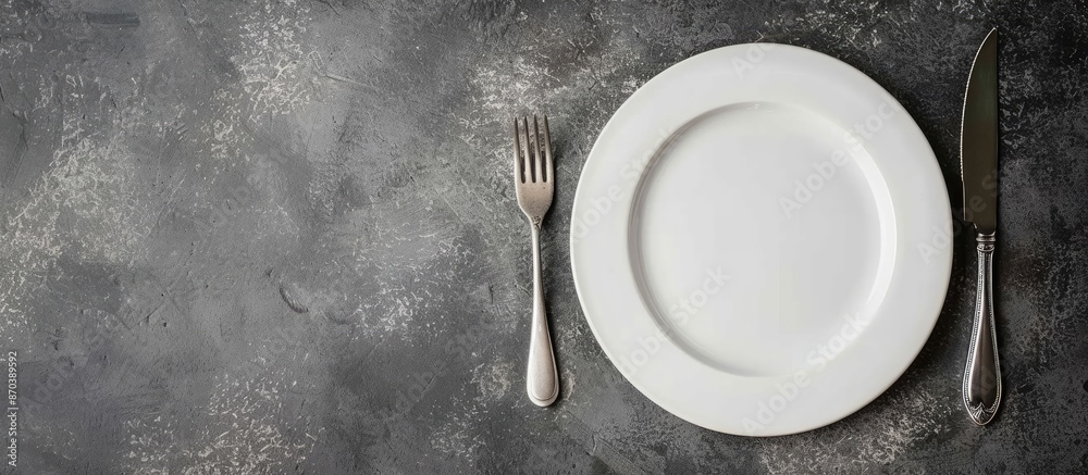 Poster Gray stone concrete table with an empty white ceramic plate, knife, and fork. Perfect for menu or recipe concepts with copy space image.