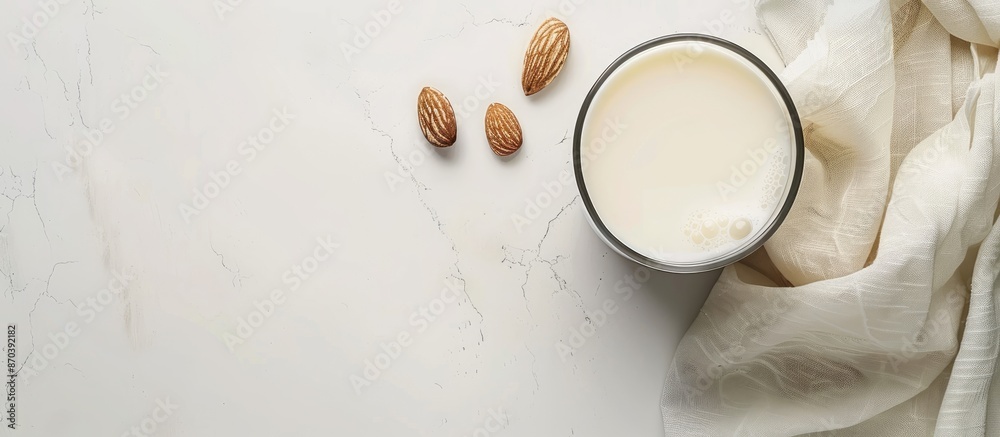 Poster Almond-based alternative milk in an unpeeled glass placed on a white table viewed from above with copy space image.