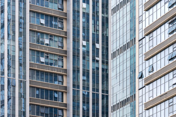Fototapeta premium A beautiful background of an glass office building, reflecting clouds in the opened windows