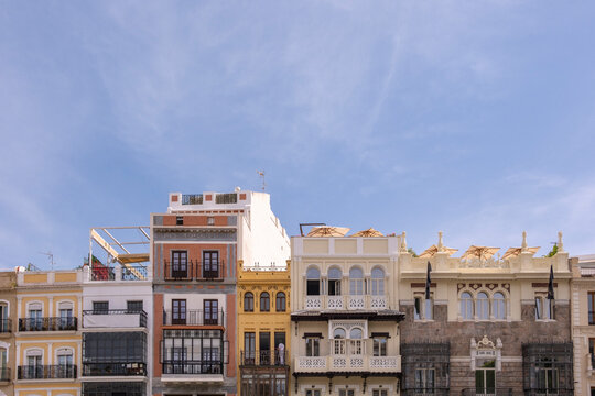 A perfect capture of lively and colorful residential building fronts with unique architectural styles under a clear blue sky, representing urban energy and cultural diversity in Seville, Spain