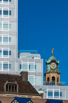 A striking image of a historical clock tower standing amidst modern office buildings, creating a visual contrast between old and new architectural styles in an urban setting in Rotterdam