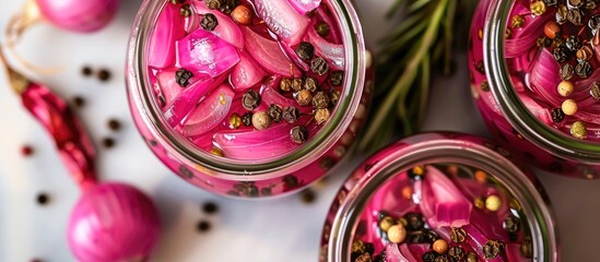 Aerial shot of pickled red onion jars with black peppercorns, showing a blank backdrop for text or graphics, known as a copy space image.