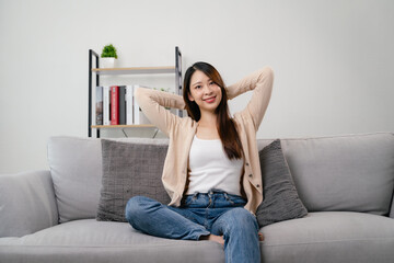 A portrait of beautiful young asian woman is sitting on a couch and smiling.