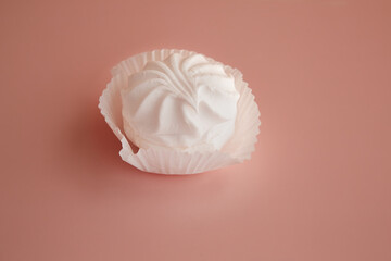 Dessert white marshmallow on delicate pink background closeup, white marshmallow in paper tartlet on pink background, delicate dessert