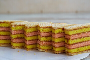 Multi-colored sponge cake slices lined up in a row on a white plate on a table