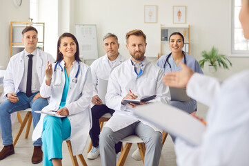 Obraz premium A group of happy doctors listens to a speaker in the audience, close-up. Medical personnel in the process of training and professional development. Seminar for the emergency department