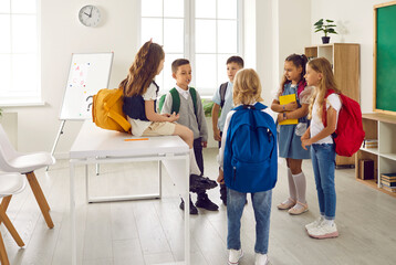 Children communicating at school. Elementary students discussing something. Group of kids gather in the classroom after lessons, talk, share news and get to know each other. Back to school concept