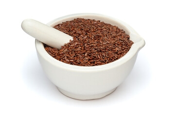 Close-up of Dry Organic Flaxseeds (Linum usitatissimum), in white ceramic mortar and pestle, isolated on a white background.