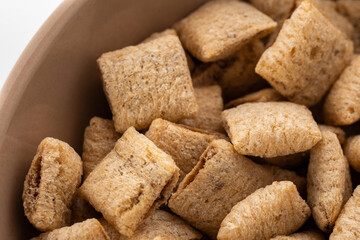 Corn snack. Cereal pads with filling falling into bowl against white background