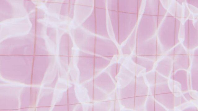 Pure pink abstract water surface in the swimming pool with light reflections texture background. Ripples and wave from sunlight.
