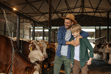 Farmer dad hugging his son and inside a barn