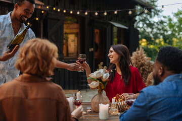 Man giving a wine glass filled with red wine to a woman