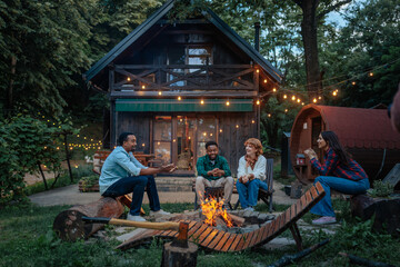 Cheerful conversation for four friends sitting around a fire pit