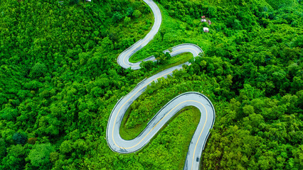 Aerial view of a road in the middle of a forest, construction of a curved road up the mountains in northern Thailand.