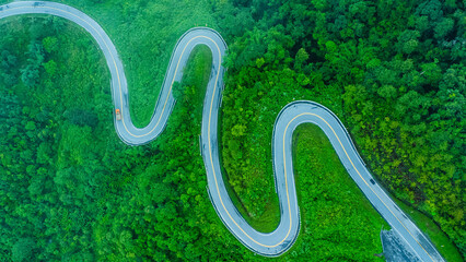 Aerial view of a road in the middle of a forest, construction of a curved road up the mountains in northern Thailand.
