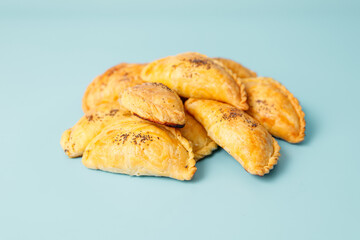 Freshly baked samosa pies with meat sprinkled with poppy seeds on blue background, central asian cuisine, copy space.