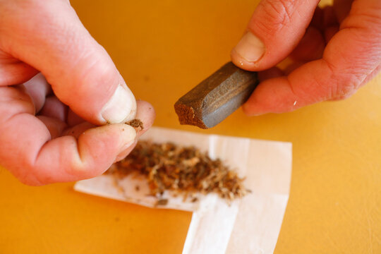 Man preparing a hashish joint. Drugs among young people.