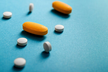White and yellow tablets and pills laid out on a blue background with copy space. Ideal for medical...