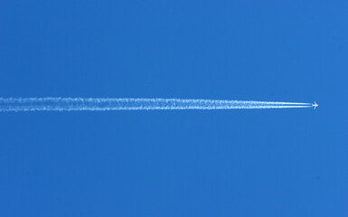 Wake of an airplane in the blue sky. Travel and air transport. Italy.