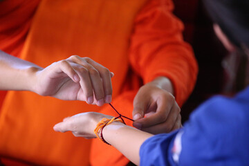  Wat Si Muang ( Simuong) buddhist temple.  Buddhist ceremony.  Monk ties blessed cotton bracetet ( Sai-sin) around a wrist. Vientiane. Laos;