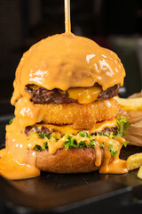 A large burger is topped with melted cheddar cheese.