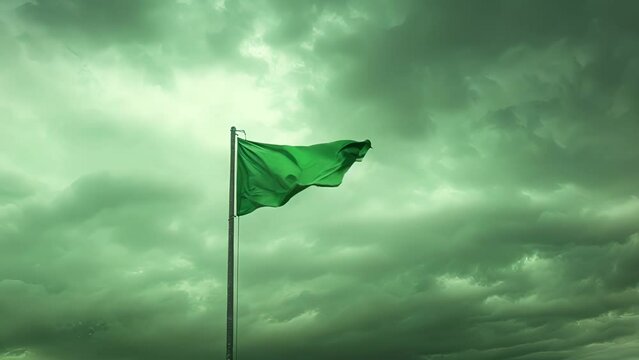 Against a backdrop of grey clouds a tattered green flag strains against its pole determined to reach new heights.