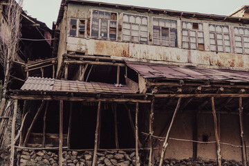 A dilapidated building with a rusted roof and broken windows