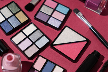 Makeup set - eye shadow, nail polishes and more on a pink background